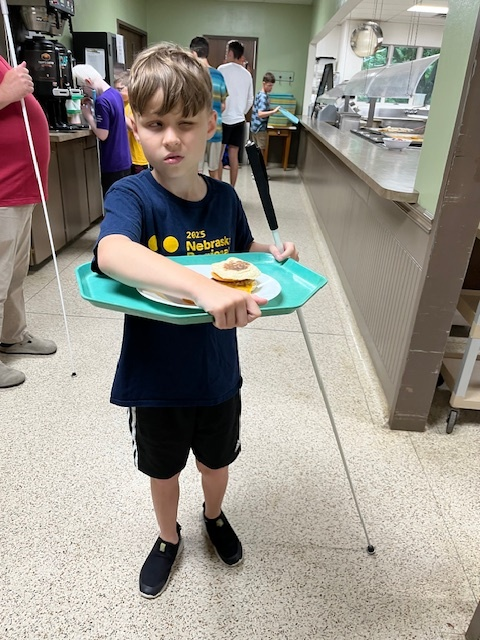 camper carrying his tray in dining hall